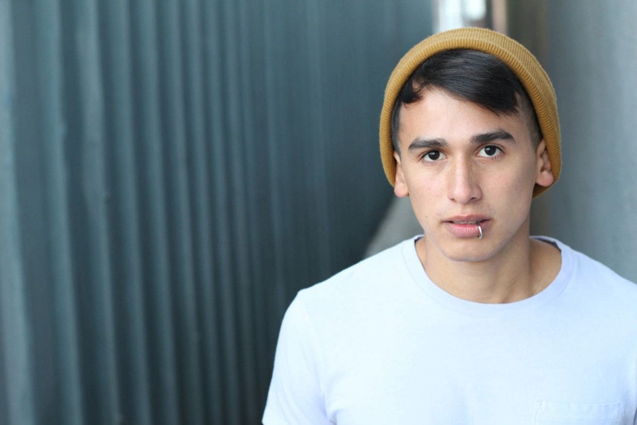 A man with a yellow hat is standing in front of a wall.